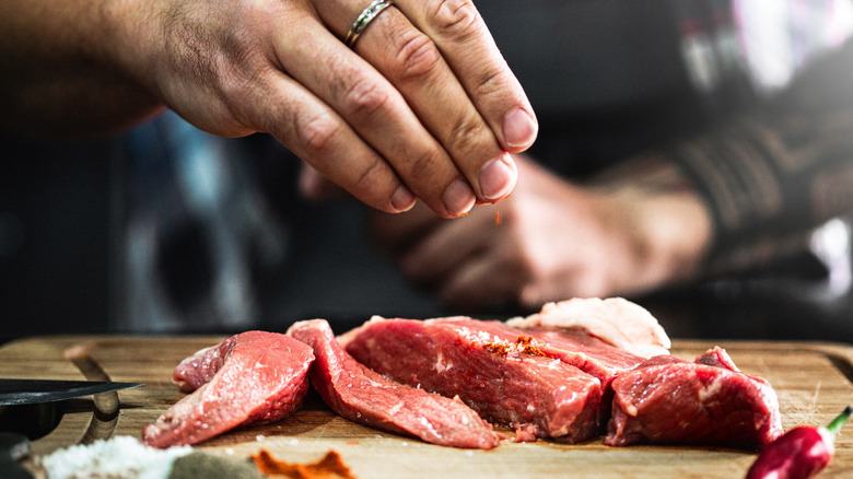 seasoning steak on a cutting board