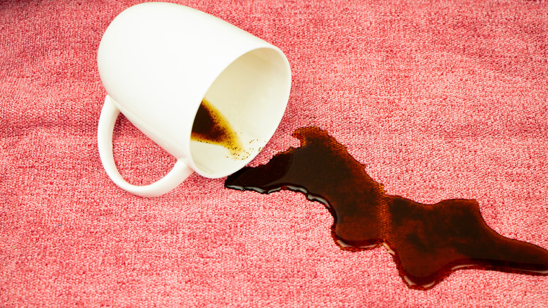 spilled cup of coffee on an orange textured tablecloth