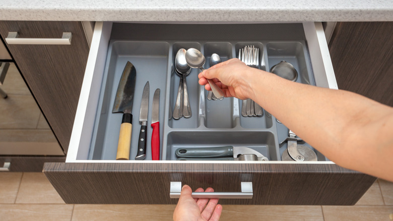hand emptying silverware drawer