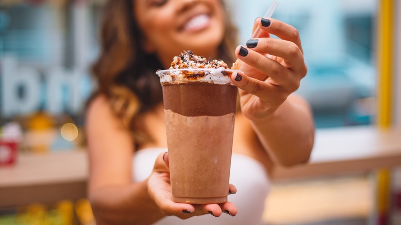 Woman holding chocolate milkshake straw