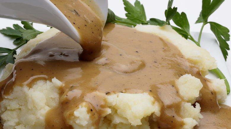 Pouring gravy over mashed potatoes