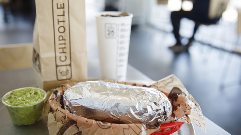 Chipotle burrito with drink, chips and guacamole