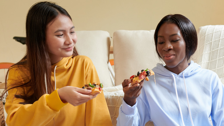 two college students eating pizza