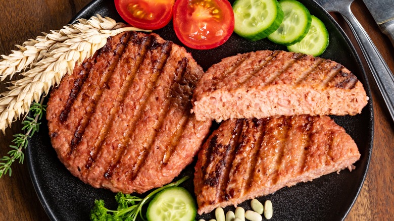 Top-down view of plant-based burger patties on a plate with veggies