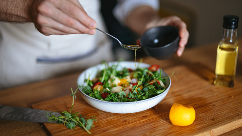 Chef drizzling oil over salad