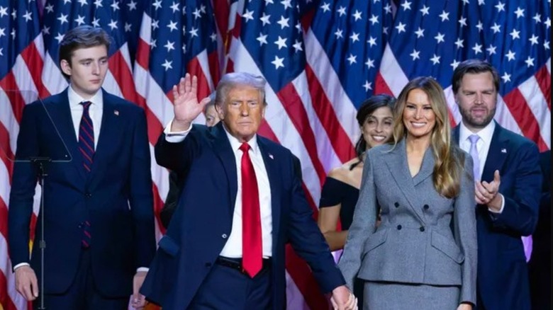 President Trump posing with his family, Vice President J.D. Vance, and Usha Vance in front of a row of American flags