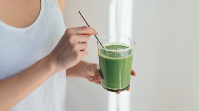 Woman holding a glass of green smoothie