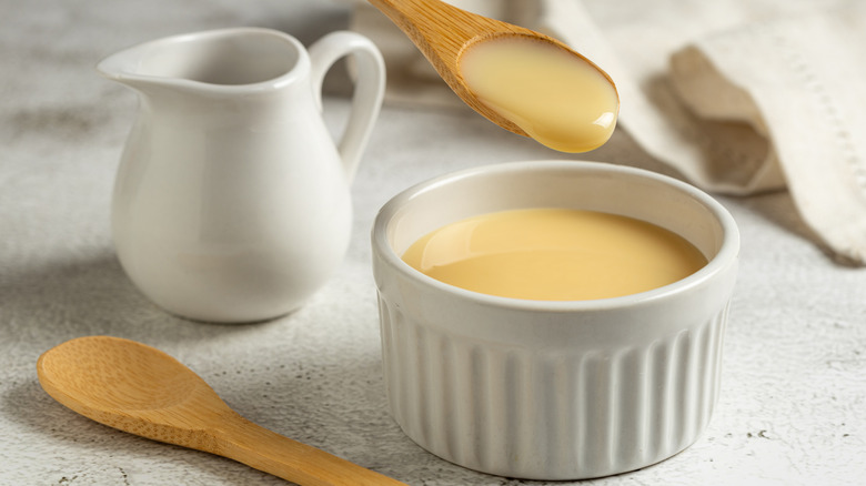 Wooden spoon dipping sweetened condensed milk out of a ramekin