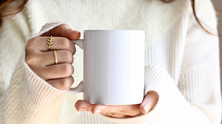 woman holding a white tea up