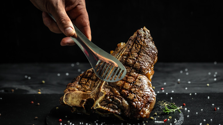 T-bone steak being held with tongs