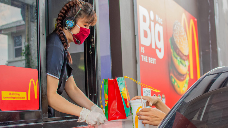 Fast food worker handing food to a customer in a car