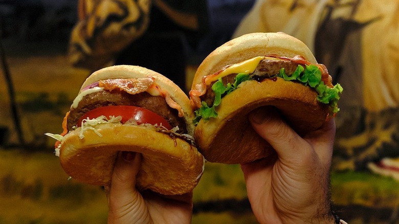 close-up people holding burgers at old wild west