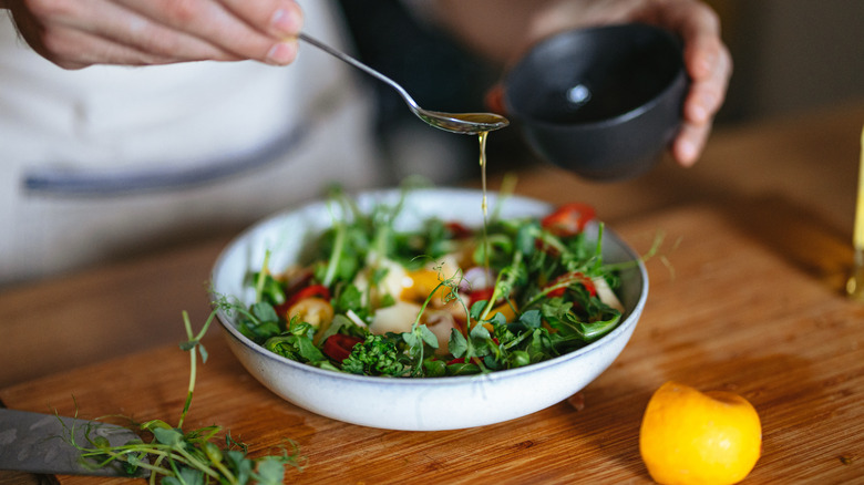 Drizzling a vinaigrette dressing over a salad 