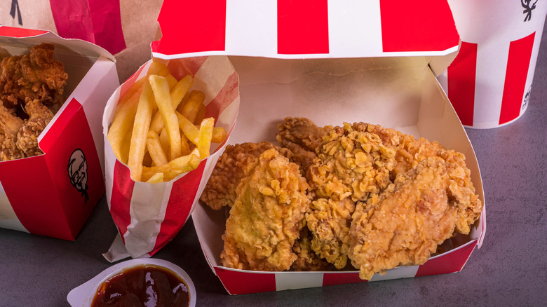 KFC food, including hot wings, a bag of fries, and a pot of BBQ sauce
