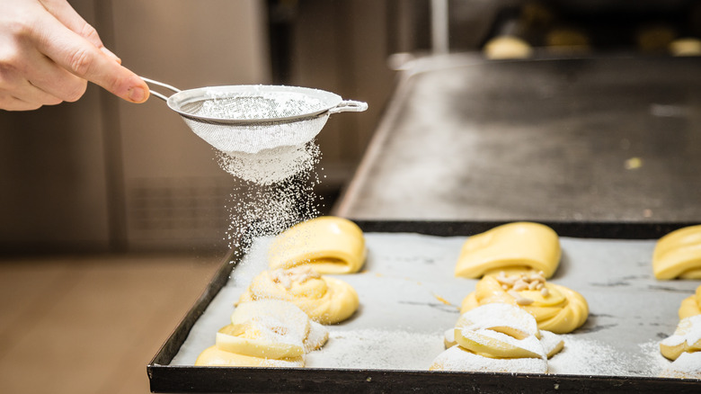 hand dusting powdered sugar on baked goods