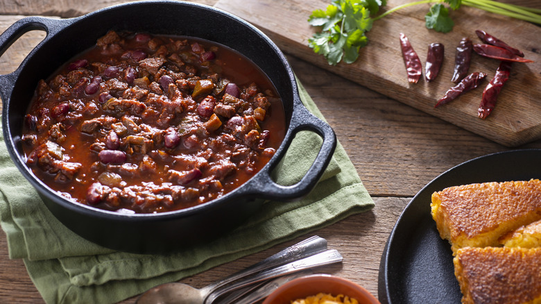 Pot of chili with cornbread and shredded cheese