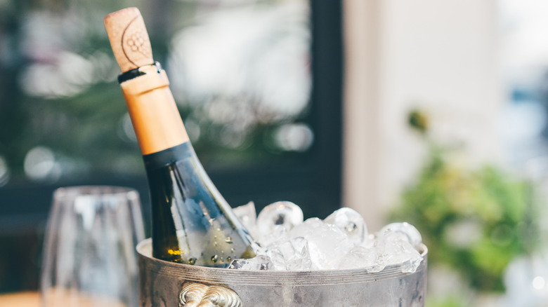 Wine bottled being chilled in metal bucket with ice