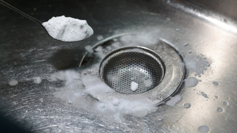 Sprinkling a spoonful of baking soda around a kitchen sink