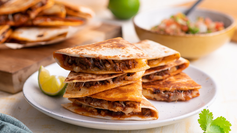 A stack of Beef quesadillas served with a lemon wedge.