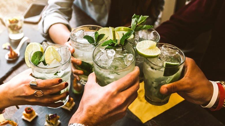 hands cheersing mojito cocktails