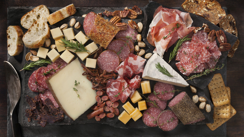 fancy charcuterie board with meats and cheeses on a dark background