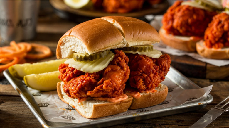 Nashville hot chicken sandwich with pickles on a metal tray