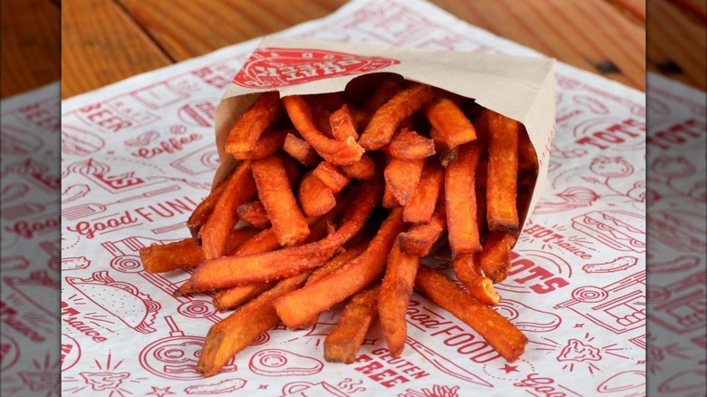 Carton of Hat Creek Burger Company sweet potato fries on restaurant-themed paper liner