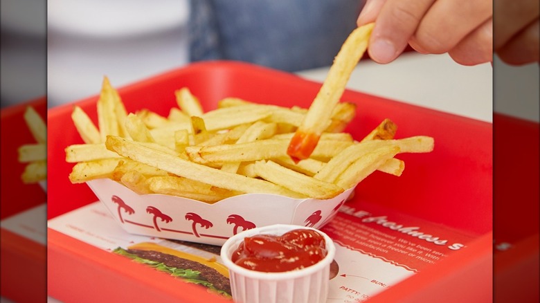 In-N-Out Burger tray of fries with unfocused ketchup-dipped fry in the foreground