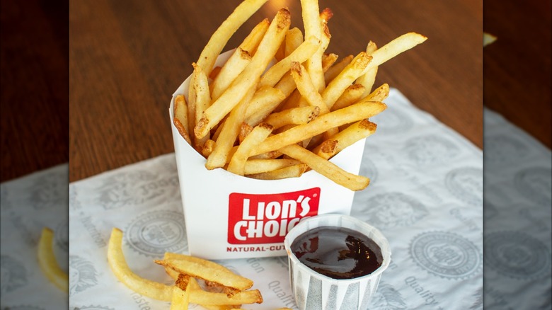 Upright carton of Lion's Choice fries with dipping sauce