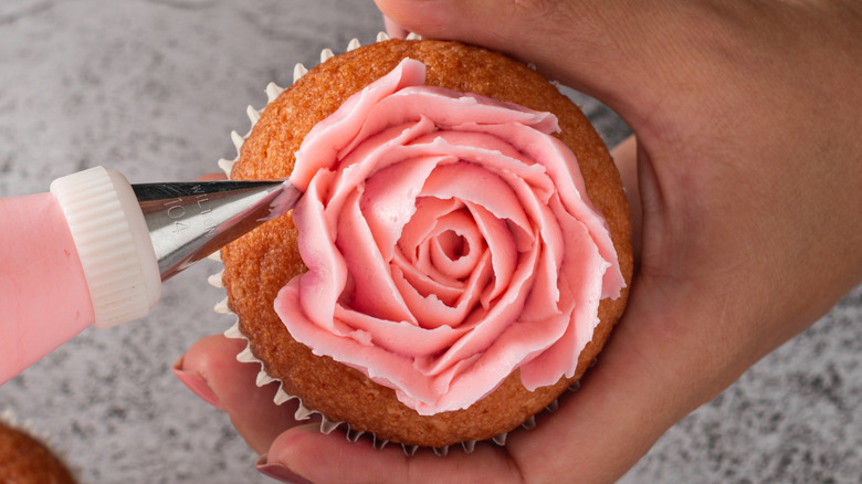 Close-up of piping frosting into a flower decoration on a cupcake