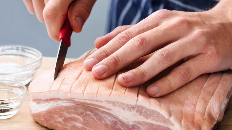 Chef scoring meat with a small knife