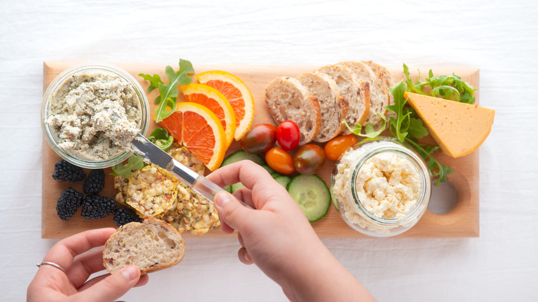 Vegan cheese board with sliced bread, fruit, and vegetables
