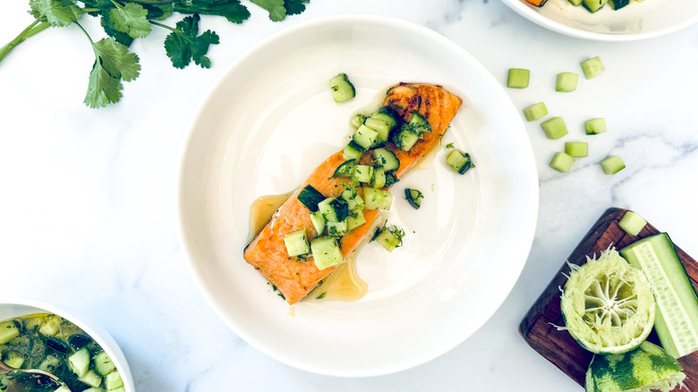salmon with cucumber topping on white plate
