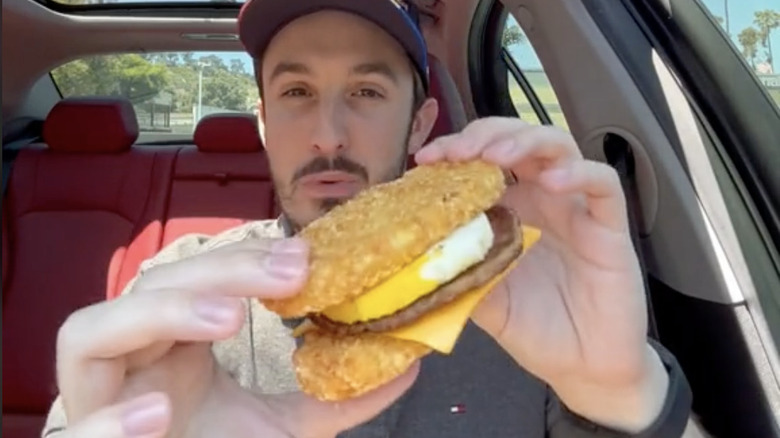 man holding hasbrown sandwich