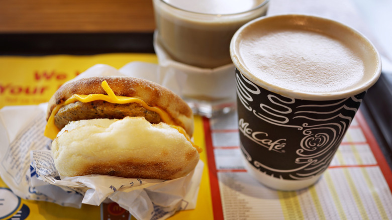 A Sausage McMuffin With Egg and a cup of McCafe coffee inside a McDonald's