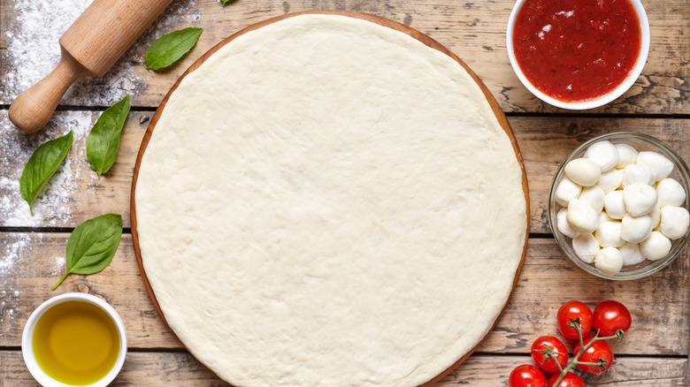 Pizza dough with sauce, oil, and cheese