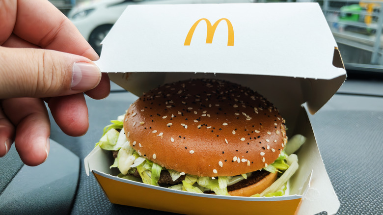 Hand opening McDonald's box to show burger