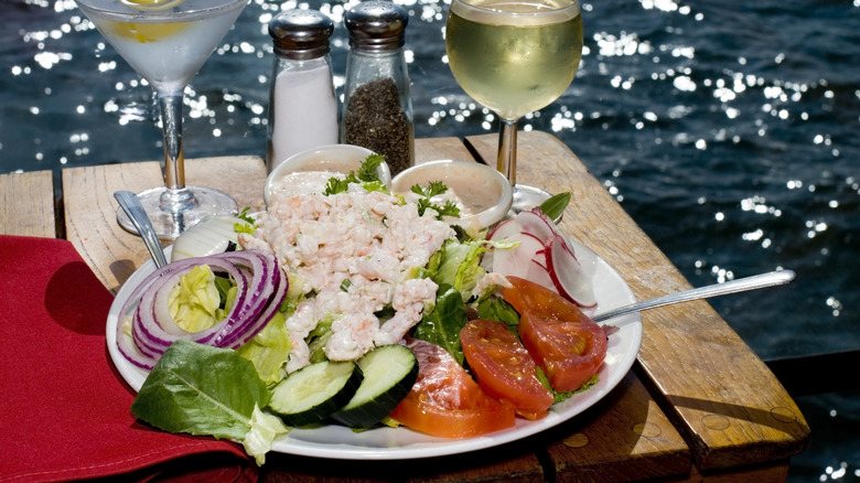 Crab Louie on a white plate on a wooden table by the ocean