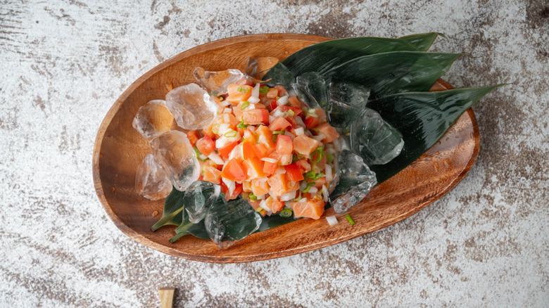 Lomi lomi salmon on a wooden plate with ice and leaves