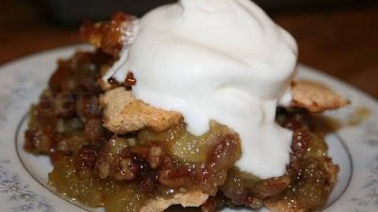 Scoop of Ozark pudding on a decorative plate garnished with whipping cream