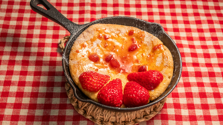 German pancake in cast iron pan garnished with fresh strawberries