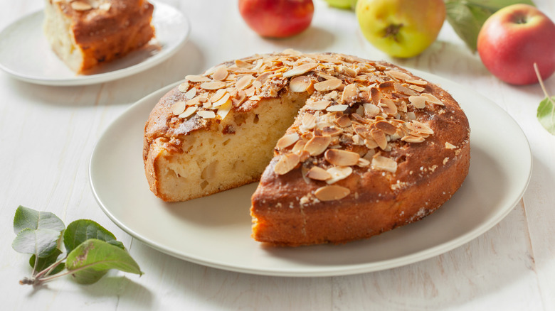 Apple kuchen garnished with shaved almond on a white plate