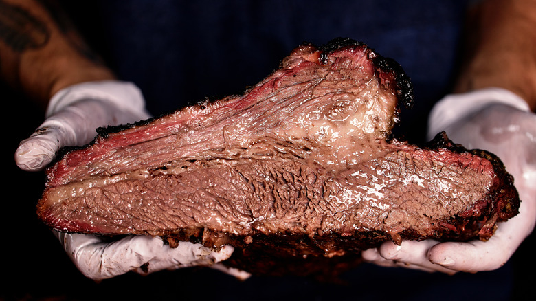 man holding brisket with glvoes