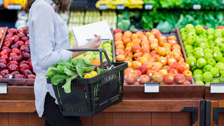 person carrying grocery basket with produce