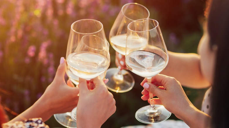 People raising sunlit wine glasses together