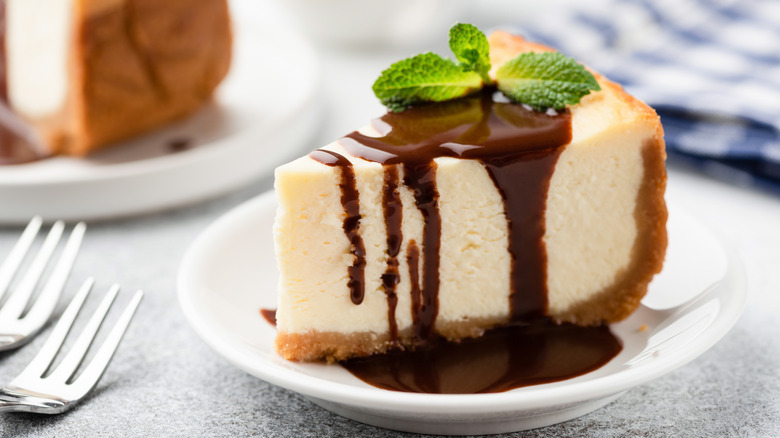 slice of plain cheesecake on a plate with chocolate sauce