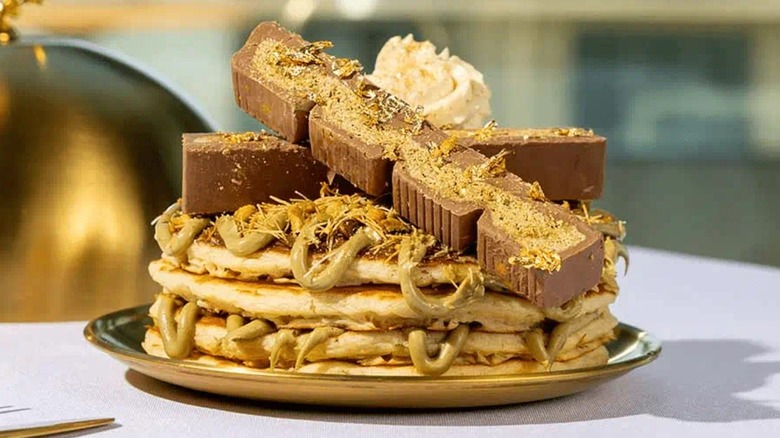 Four pancakes topped with Dubai chocolate, whipped cream, and pistachio cream