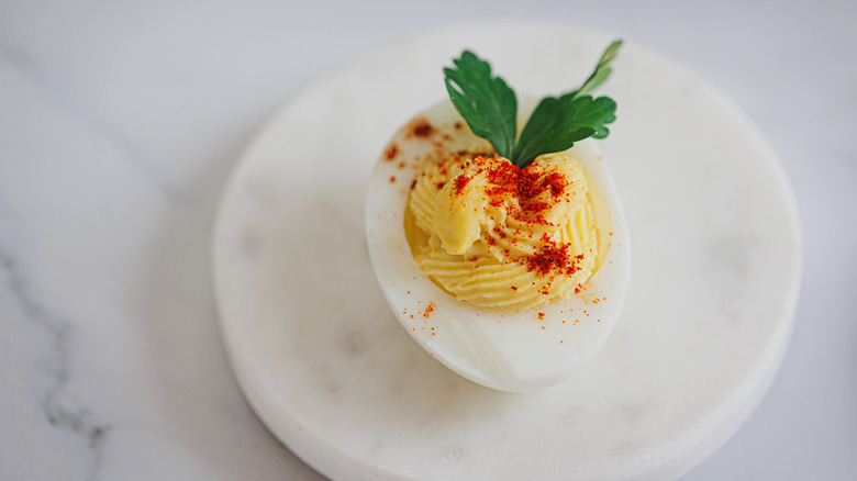 single deviled egg on white marble
