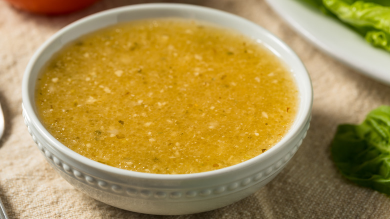 Bowl of salad dressing next to salad