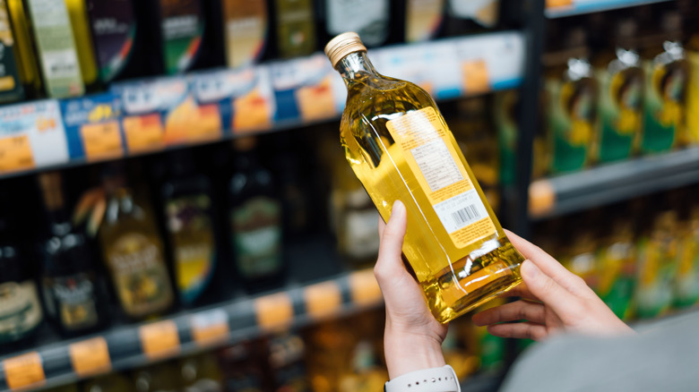 Person choosing cooking oil in grocery store.